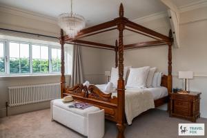 a bedroom with a wooden canopy bed and a chair at The Plas - Rhosneigr Manor House in Rhosneigr