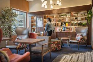 a woman walking into a restaurant with chairs and tables at Point A Hotel Edinburgh St Andrew Square in Edinburgh