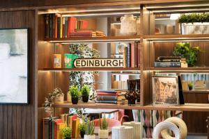 a book shelf with books and plants on it at Point A Hotel Edinburgh St Andrew Square in Edinburgh +46 photos