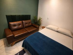 a bedroom with a bed and a leather couch at Suite 02 in Barcarena