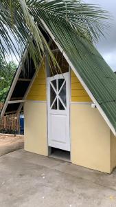 a yellow building with a white door and a palm tree at Casa da Raposa in Iguaíba