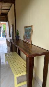 a wooden table with a bench and a picture at Casa da Raposa in Iguaíba +21 photos