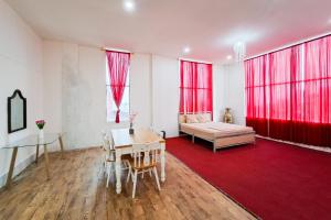 a living room with a table and a bed and red curtains at RedDoorz at Pasifik Hotel Sabang Aceh in Sabang