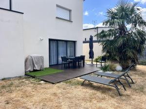 a wooden deck with a table and chairs in a yard at L'Océane Maison avec jardin in Vannes