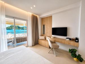 a hotel room with a bed and a desk with a television at Ventora Suites in Nydri