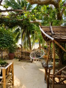 a patio with a hammock and a chair under a tree at Tea Moon Boutique Stay in Thong Sala
