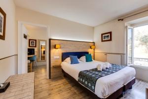 a bedroom with a large bed with blue pillows at Hôtel Saint Albert in Sarlat-la-Canéda +50 photos