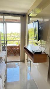 a bedroom with a desk with a television and a balcony at Gran Lençóis Flat - Barreirinhas -MA in Barreirinhas