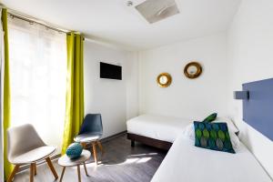 a bedroom with a bed and two chairs and a window at Hôtel Saint Albert in Sarlat-la-Canéda