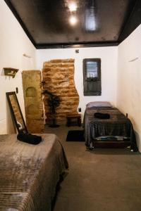 a room with two beds and a stone wall at Alto Saudade - Atins in Barreirinhas
