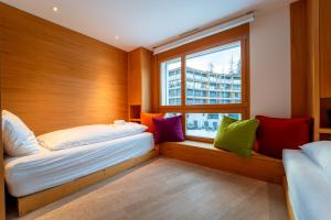 two beds in a room with a window at Sleek Mountain Escape Light and Airy in Flims