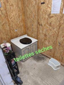 a toilet in a room with a wooden wall at Maisonnette de campagne in Val Couesnon