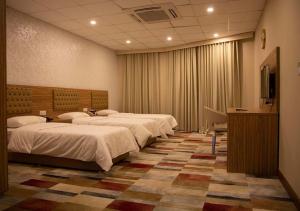 a row of four beds in a hotel room at Rawaz Hotel in As Sulaymānīyah