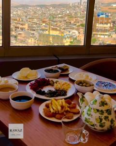 a table with plates of food on a table with a window at Rawaz Hotel in As Sulaymānīyah
