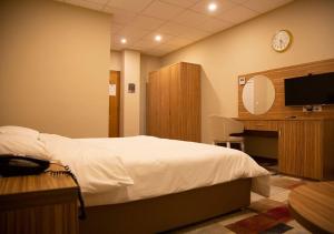 a bedroom with a bed and a desk and a tv at Rawaz Hotel in As Sulaymānīyah