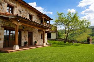 a stone building with a grass yard and a bench at La Casa de Bustantegua in Selaya