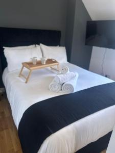 a bed with a tray of towels and a table on it at Spacious 4-Bedrooms Corporate Flat - Prime Location in Watford