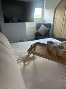 a bed with two cups on a wooden tray on it at Spacious 4-Bedrooms Corporate Flat - Prime Location in Watford +28 photos