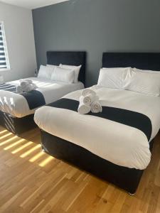 two beds in a hotel room with towels on them at Spacious 4-Bedrooms Corporate Flat - Prime Location in Watford