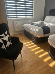 a bedroom with two beds and a chair and a window at Spacious 4-Bedrooms Corporate Flat - Prime Location in Watford