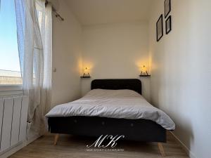 a bed in a room with two lamps on the wall at L'Arche in Saint-Dizier