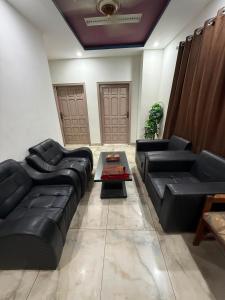 a living room with black leather couches and a table at Khushal Residence in Peshawar