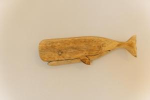 a wooden fish shaped object hanging on a wall at Always Boutique Stay 2 in Kampong Huaibū