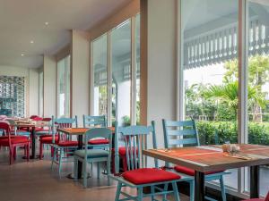 a restaurant with tables and chairs and windows at Ibis Styles Phuket City in Phuket