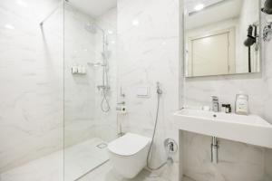 a white bathroom with a shower and a toilet and a sink at Brosse Garden in Tbilisi City