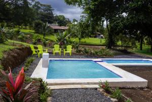 a swimming pool in a yard with green chairs at Divan Jungle Lodge in Fortuna