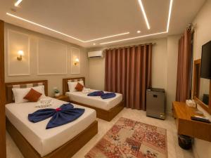 a hotel room with two beds and a television at Garden Hotel Nile House in Cairo