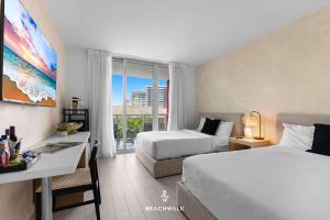 a hotel room with two beds and a desk and a window at Pininfarina Studio Intracoastal View in Hallandale Beach