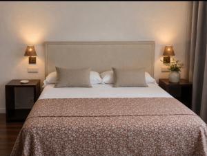 a bedroom with a large bed with two tables and two lamps at El Linar in Burgohondo