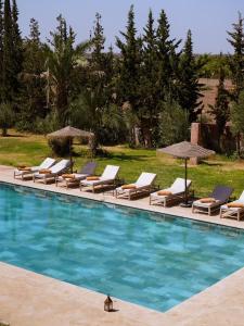 a group of lounge chairs and umbrellas next to a swimming pool at Villa zitoun in Aït Bou Zguia