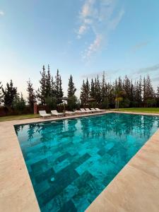 a swimming pool with blue water and lounge chairs at Villa zitoun in Aït Bou Zguia