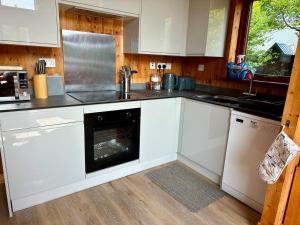 a kitchen with white cabinets and an oven at Lochside Lodge in Dallavich +29 photos