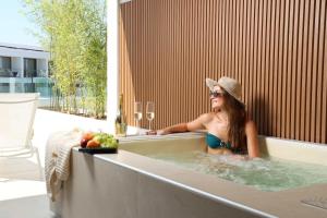 a woman in a bath tub with a hat at Sophe Boutique Stay 2 in Kallithea Halkidikis