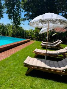 two lounge chairs and an umbrella next to a pool at Casa da Costeira in Figueiró