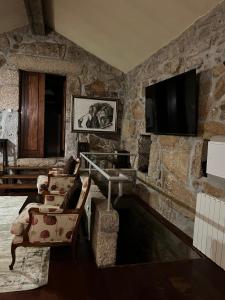 a living room with a stone wall with a tv at Casa da Costeira in Figueiró