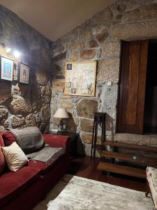 a living room with a red couch and a stone wall at Casa da Costeira in Figueiró +129 photos