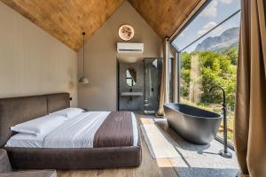 a bedroom with a tub and a bed with a view at North Alpine Villas in Bogë