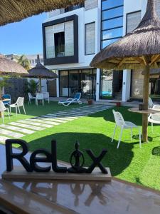 a sign in front of a house with chairs and tables at Appartement Zen VIP Péreybère in Grand-Baie