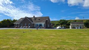 a house on a field with two birds in the grass at B&B Kerry Lakesview Lodge in Waterville +71 photos