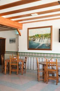 a dining room with tables and chairs and a painting on the wall at Hostal Guadiana in Ruidera