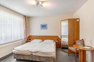 a bedroom with a bed and a table and a chair at Hotel Zum Wikinger in Dornum