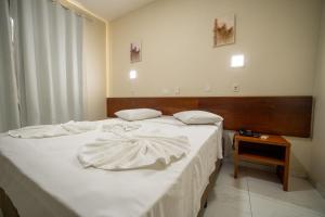 a bedroom with a bed with white sheets and a table at Hotel Dan Inn Express Foz do Iguaçu By Nacional Inn in Foz do Iguaçu