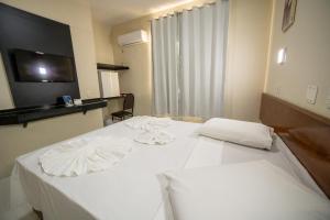 a hotel room with two beds with white sheets at Hotel Dan Inn Express Foz do Iguaçu By Nacional Inn in Foz do Iguaçu