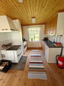 a kitchen with white cabinets and a wooden ceiling at Gårdshus in Lit