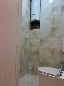 a bathroom with a toilet and a stone wall at Lux Apart in Khujand