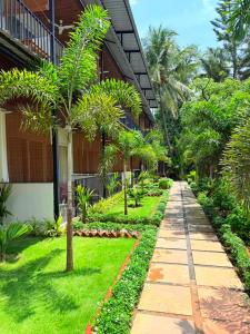 a walkway in front of a house with palm trees at Orange Sky Inn in Canacona